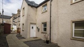A residential building with a white door, a satellite dish, and a small window with a shutter.