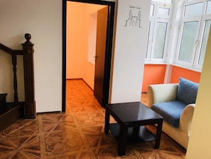 A living room with a patterned floor, a wooden staircase, a sofa, and a small table.