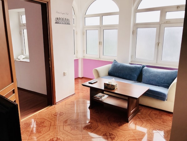 A room with a sofa, a coffee table, and a window.