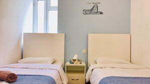 Une chambre d’hôtel avec deux lits, une petite table de chevet avec une boîte de mouchoirs et un élément décoratif mural.