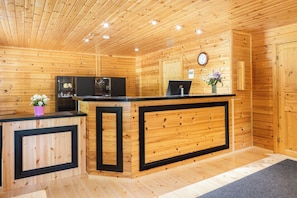 A wooden interior with a reception desk, a clock, and a small flower arrangement. - Hapimag Resort Punkaharju (Savonlinna)