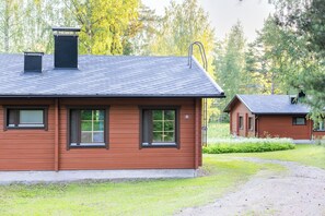 A wooden cabin with a sloped roof, a chimney, and a small attached shed. - Hapimag Resort Punkaharju (Savonlinna)