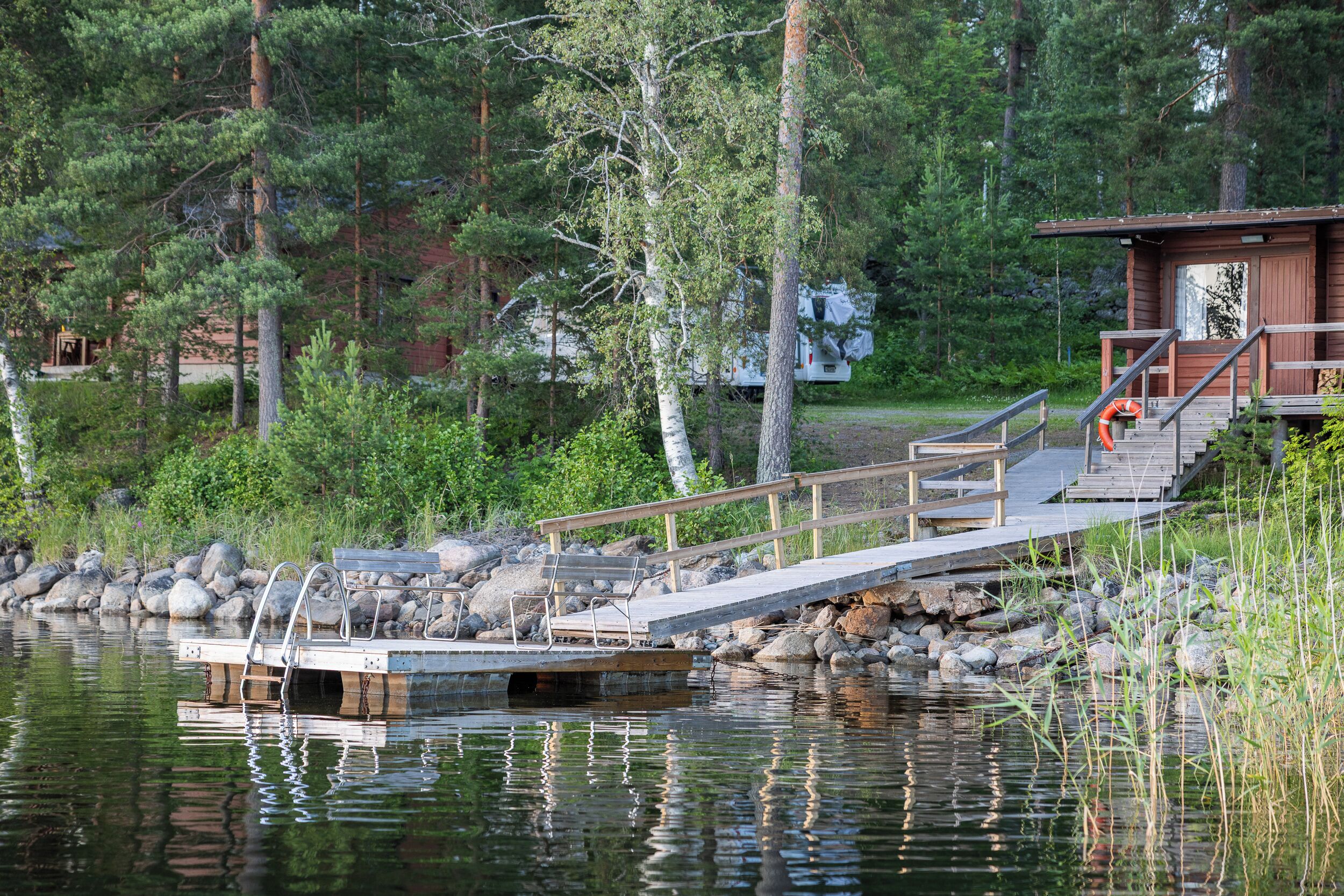 A wooden dock extending into a calm lake, surrounded by dense forest.