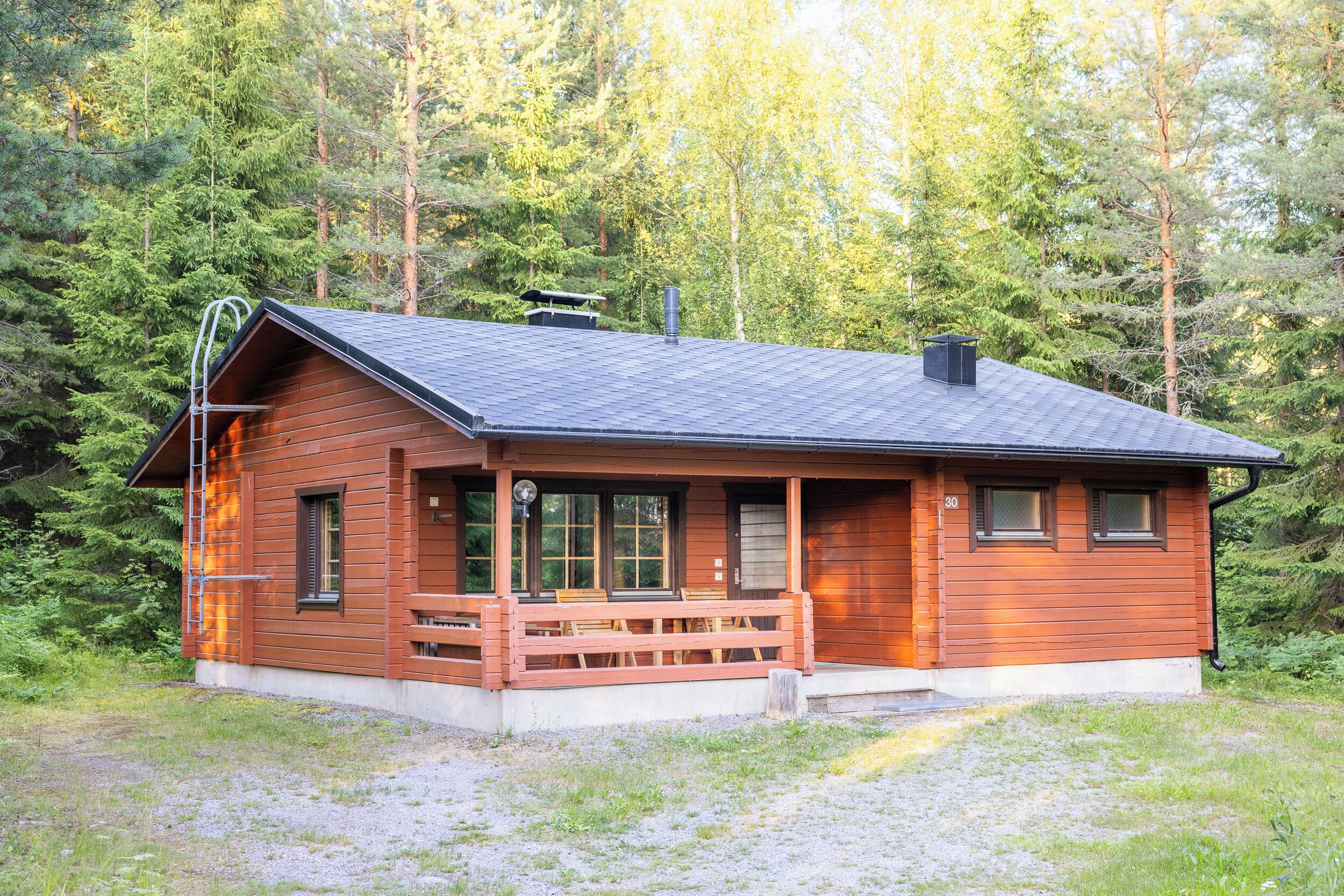 A cabin with a porch, large windows, and a chimney.