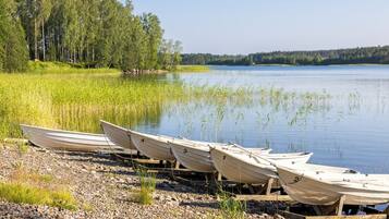 Diverses barques amarrades a moll de fusta vora un llac tranquil, amb un bosc al fons.