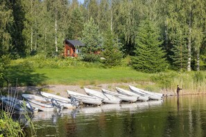 A lakeside scene with several boats docked near a house surrounded by dense forest. - Hapimag Resort Punkaharju (Savonlinna)