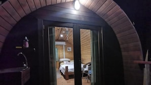 Acogedora habitación tipo cabaña con techo de madera, una cama, una silla y una mesita.