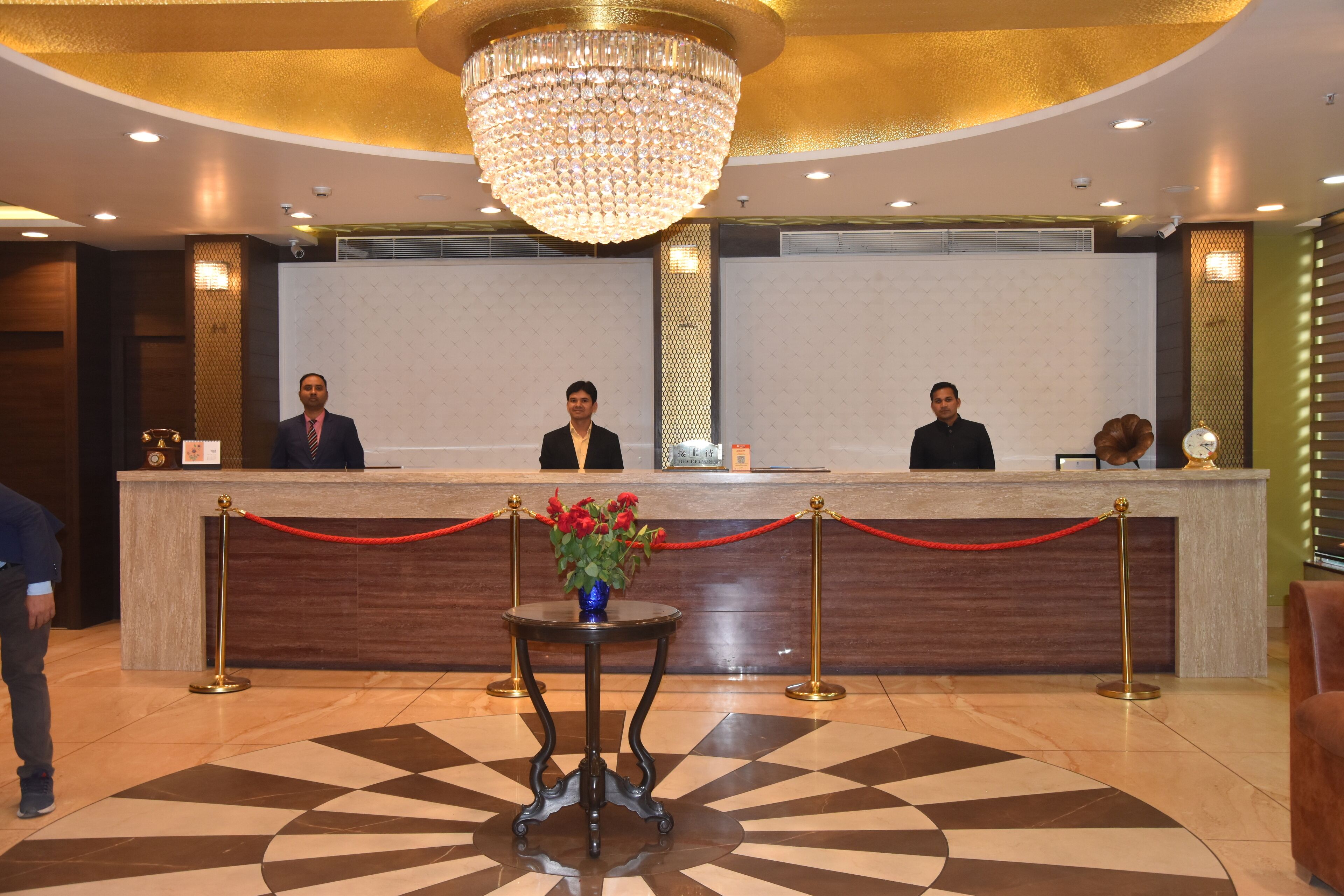 Ein Hotel-Empfangsbereich mit Marmorboden, einem Kronleuchter und einer Rezeption.