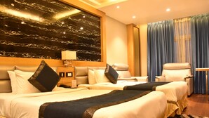 A hotel room with two beds, a large marble wall, a blue curtain, and a small table. - The Grand Empire A Boutique Hotel (Patna)