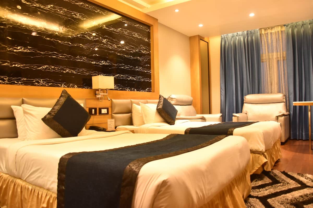 Une chambre d’hôtel avec deux lits, un grand mur en marbre, un rideau bleu et une petite table.