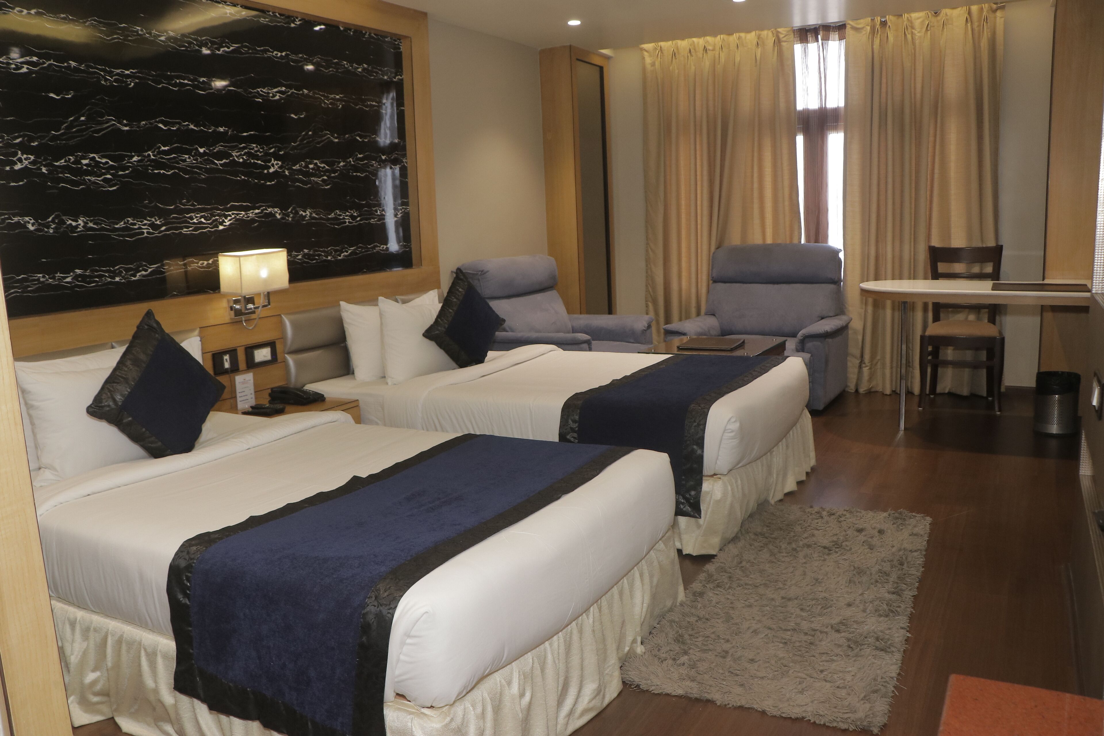 Une chambre d’hôtel avec deux lits, un bureau, une chaise et un grand miroir.
