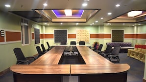 A conference room with a long wooden table, black chairs, and a cushioned seating area. - The Grand Empire A Boutique Hotel (Patna)
