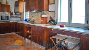 A kitchen with wooden cabinets, a built-in oven, and a window with a view. - Alekos Beach Houses-Infinity (Kefalonia)