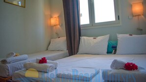 A hotel room with two beds, each with white linens and pillows, a window with curtains, and a wall-mounted lamp. - Alekos Beach Houses-Infinity (Kefalonia)