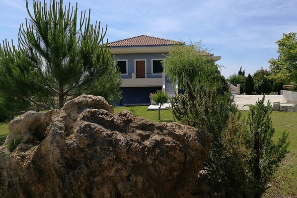 A two-story house with a tiled roof, a front porch, and a well-maintained lawn.