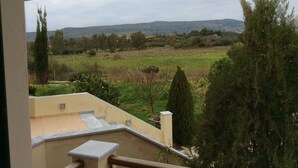 A view from a balcony overlooking a rural landscape with hills in the distance. - Alekos Beach Houses-Angelo (Kefalonia)