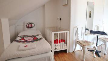 A bedroom with a crib, a chair, and a desk.