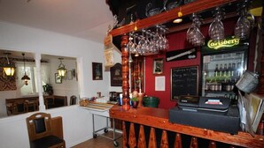 Zona de bar con mostrador de madera, copas colgantes y vitrina refrigerada.