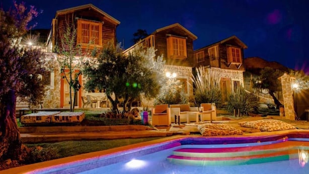 A multi-story building with a pool area, outdoor seating, and a stone facade.
