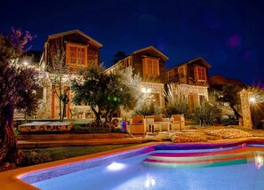 Un edificio de varios pisos con piscina, zona de estar al aire libre y fachada de piedra.