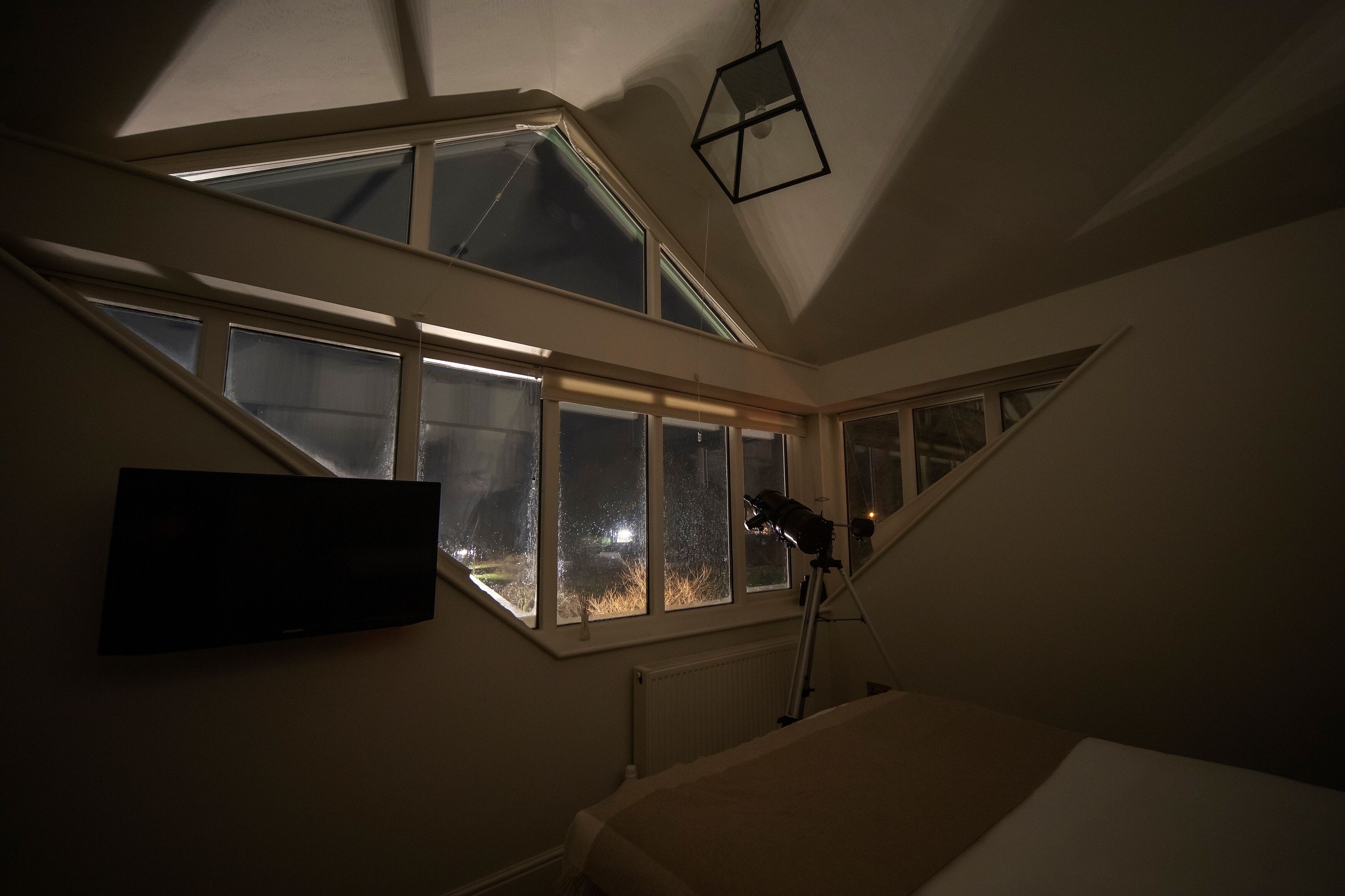 A room with skylights, a bed, and a desk lamp.