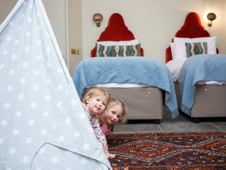 A bedroom with two beds, a red headboard, and a patterned rug.