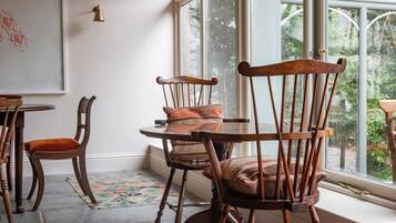 Un espace repas avec des chaises et une table en bois, un tableau blanc et une vue sur la verdure à l’extérieur.