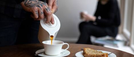 Une personne verse du café dans une tasse posée sur une table, à côté d’une part de gâteau.