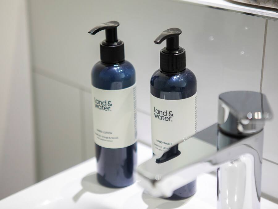 Two bottles of hand lotion and a faucet on a bathroom sink.