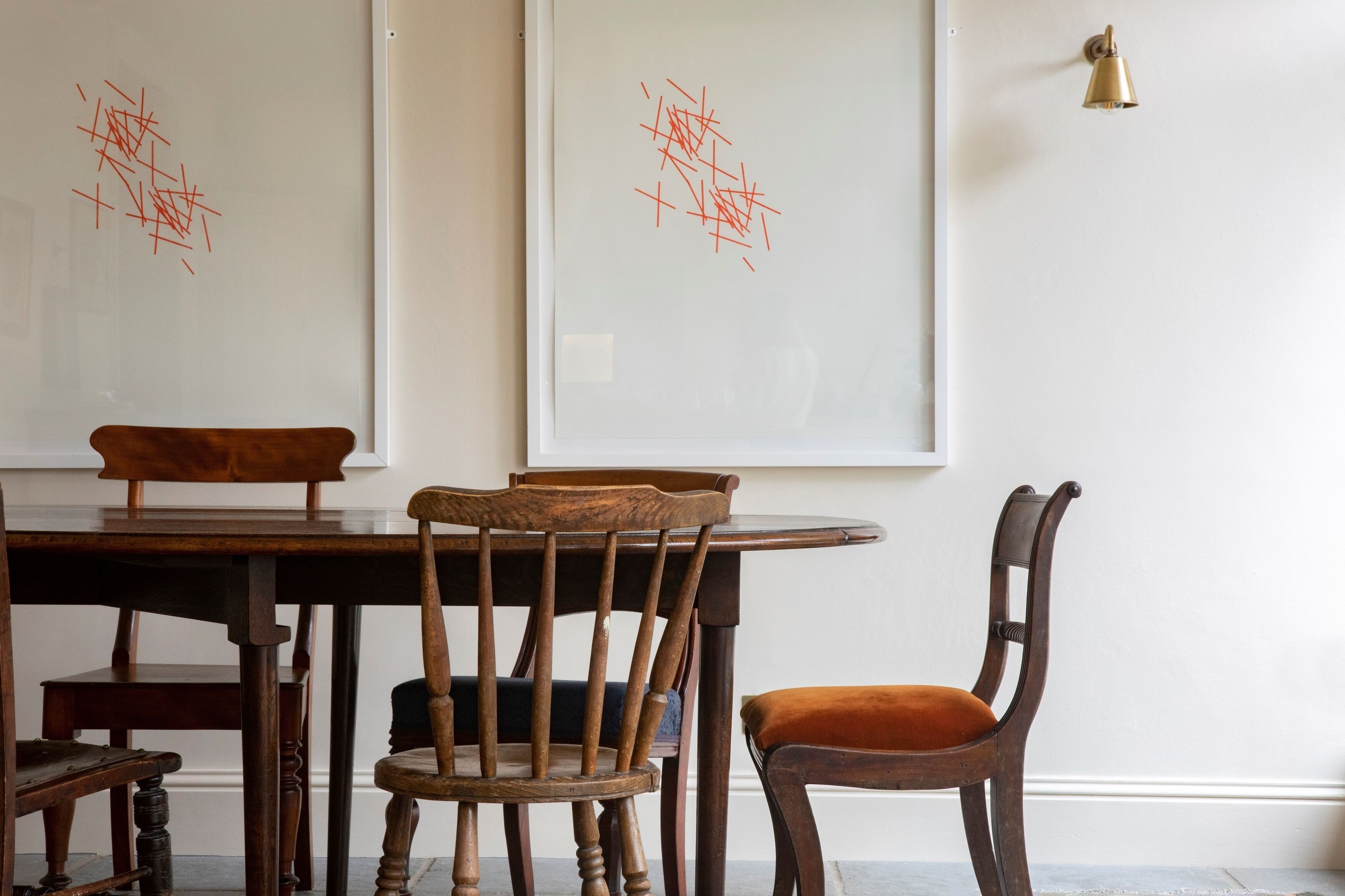 A dining area with a wooden table and chairs, a whiteboard with red markings, and a wall-mounted light fixture.