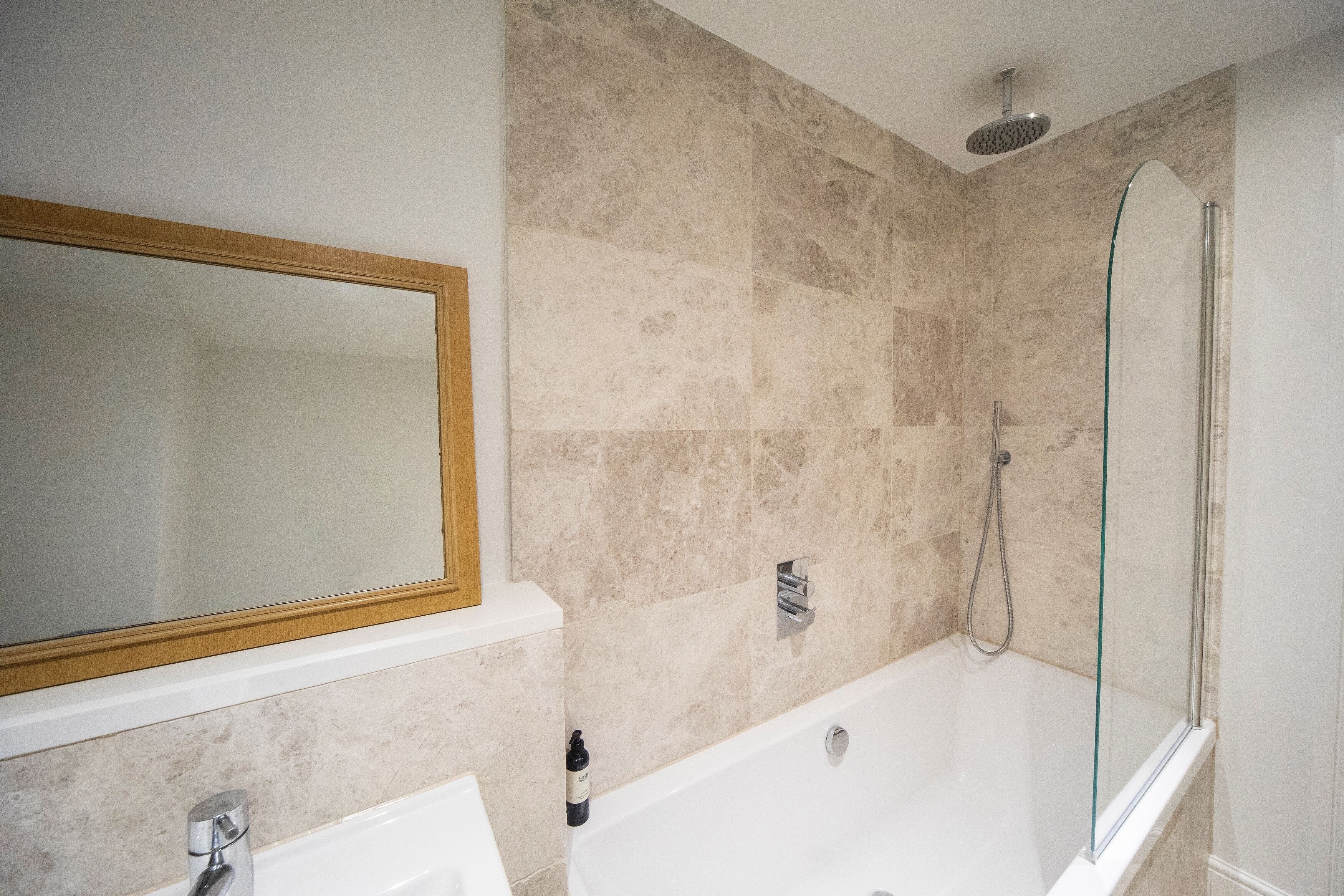 A modern bathroom with a glass-enclosed shower, a freestanding bathtub, and a large mirror above the sink.