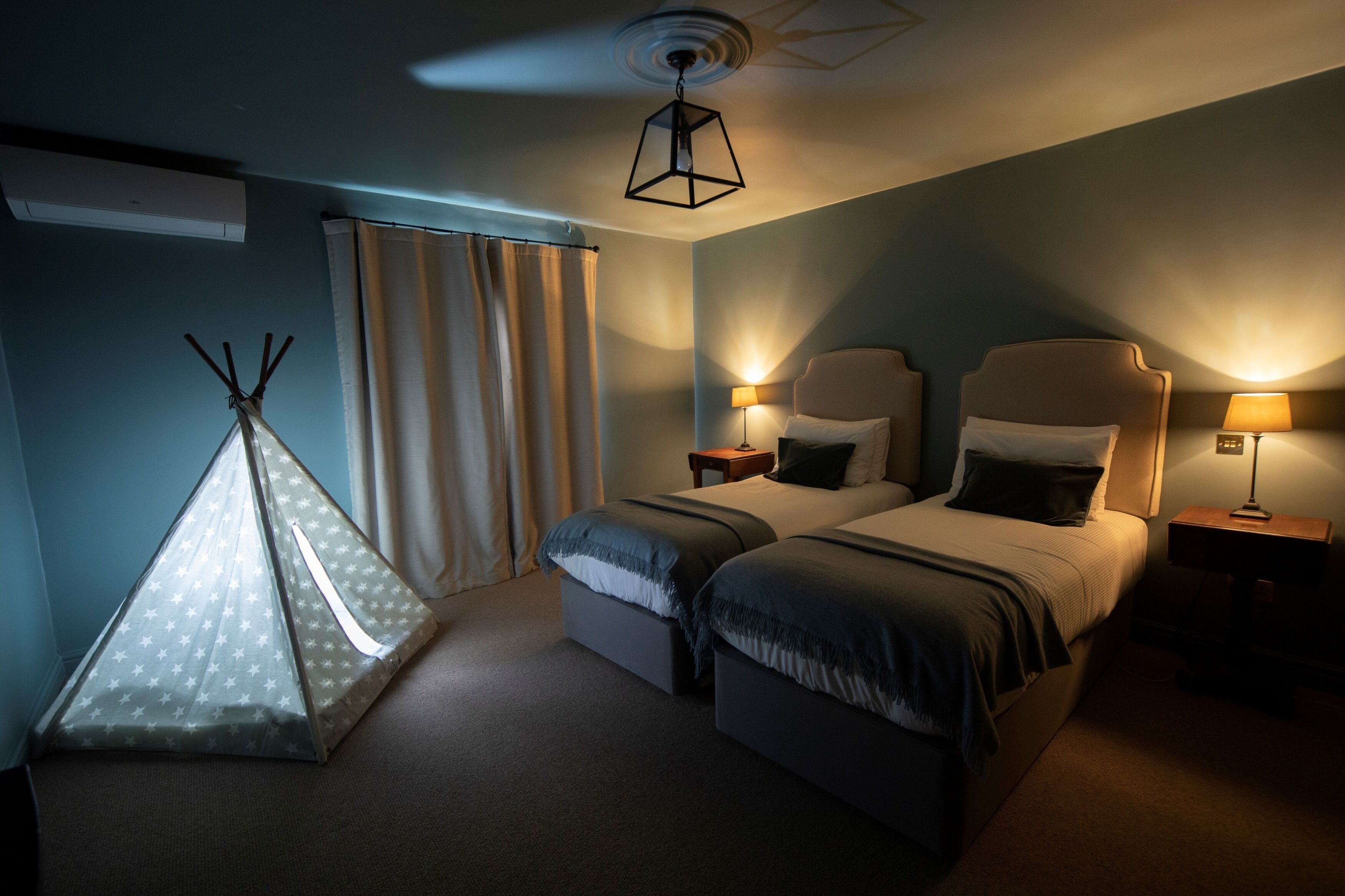 A hotel room with two beds, a ceiling fan, and a teepee.