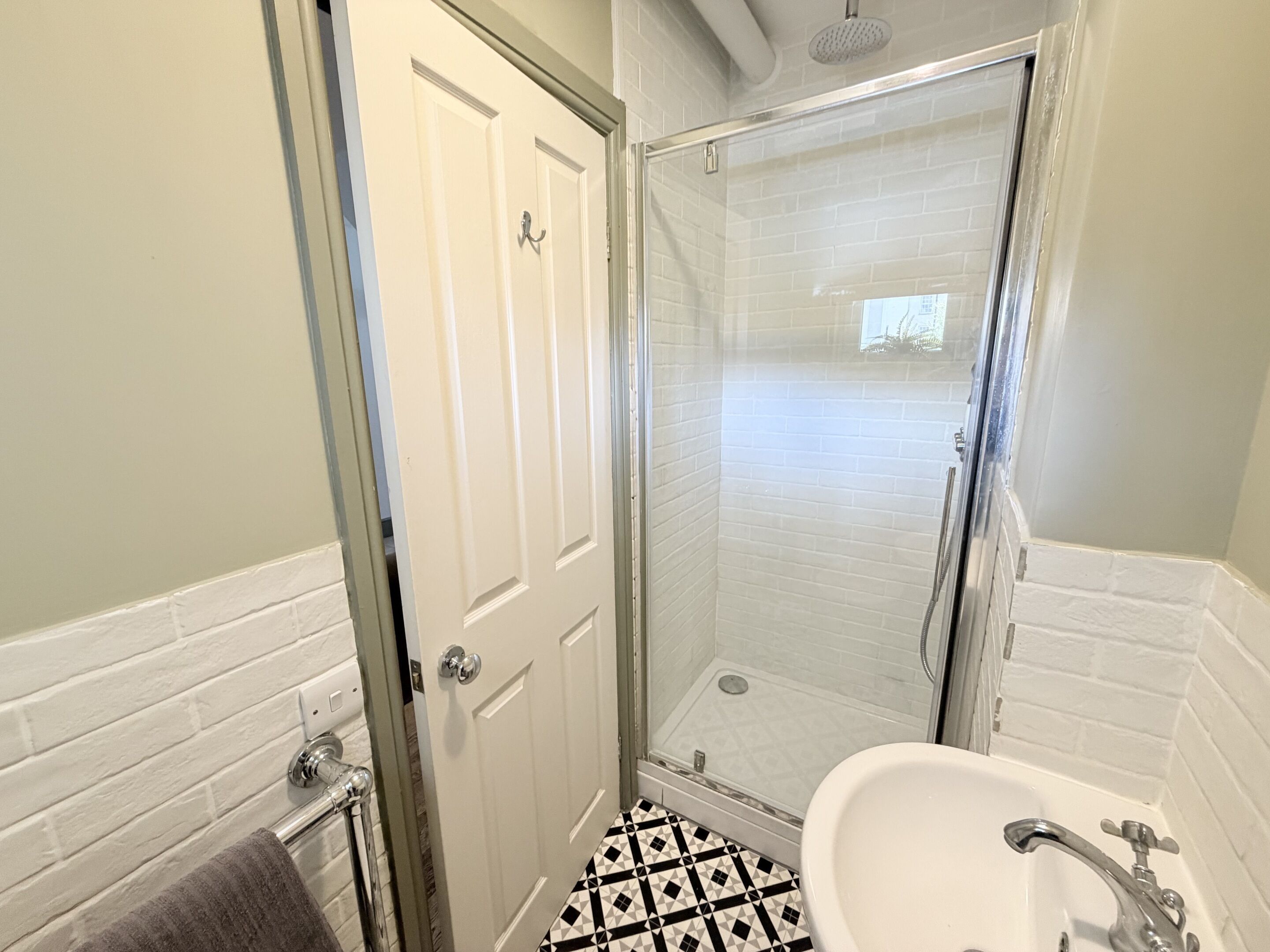 A bathroom with a shower, a sink, and a door.