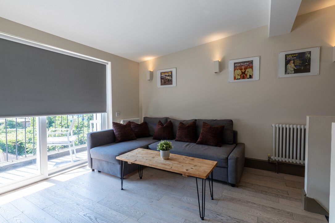 A modern living room with a grey sectional sofa, a wooden coffee table, and a large window with a view of greenery.