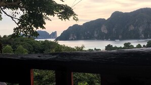 Une vue depuis une terrasse en bois donnant sur une étendue d’eau, avec des montagnes en arrière-plan.