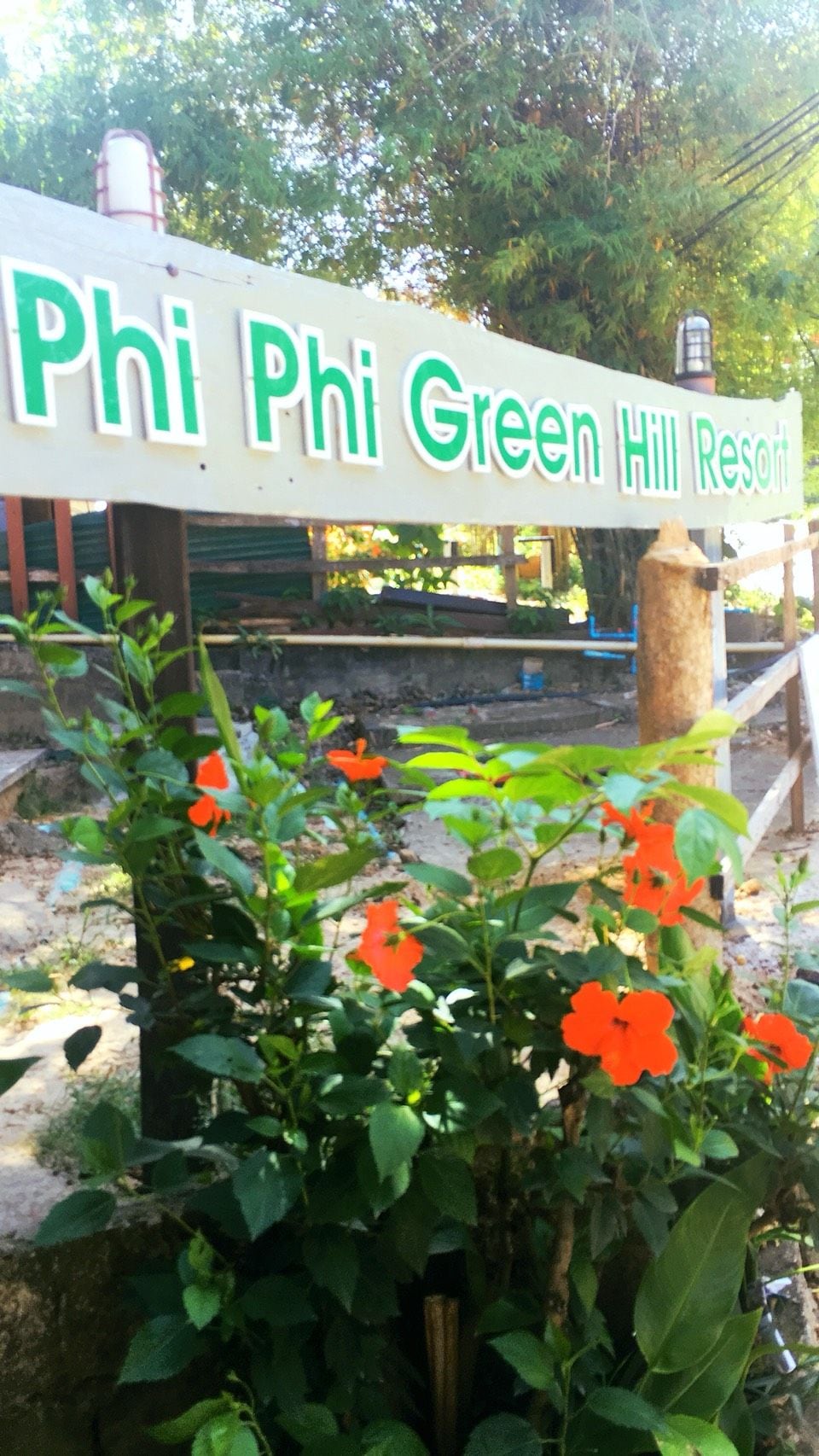 A sign for Phi Phi Green Hill Resort with a garden in the foreground.
