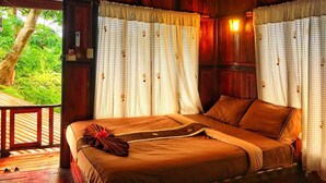 Une pièce en bois avec un lit, des rideaux et une vue sur la verdure.