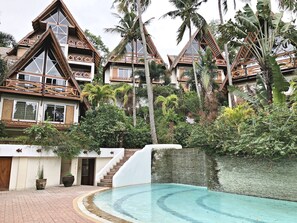 Un resort con varias construcciones tipo bungaló, una piscina y exuberante vegetación tropical.