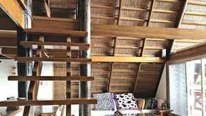 A wooden interior with a sloped ceiling, a glass table, and a curved wooden chair. - Waimea Luxury Houses - Adults Only (Puerto Galera)