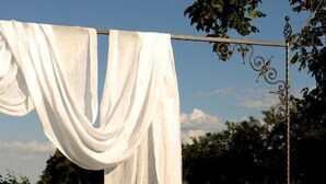 A rooftop terrace with a white cloth hanging, a stone bench, and two floral cushions. - Agrisalotto (Cortona)