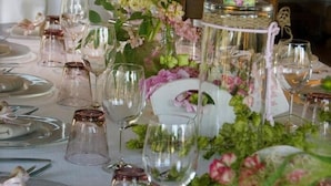 A table set for a formal event with clear glassware, plates, and a tiered centerpiece with flowers. - Agrisalotto (Cortona)