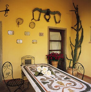 Un comedor con una mesa dispuesta para dos, una silla, un ventanal con vistas y una planta de cactus.