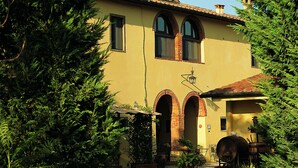 A two-story building with a yellow facade, arched windows, and a tiled roof. - Agrisalotto (Cortona)