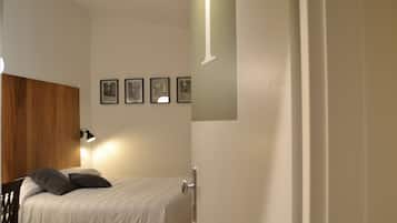 Un dormitorio con una cama, cabecera de madera, mesita de noche, lámpara de pared y cuadros en la pared.