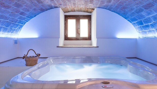 A hot tub in a room with a sloped ceiling and a window. - Albergo Il Rientro (Cannara)