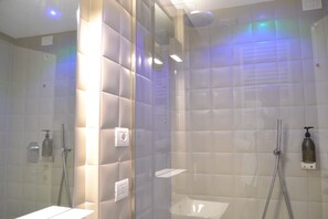 A modern bathroom with a glass-enclosed shower, a white sink, and a handheld showerhead.
