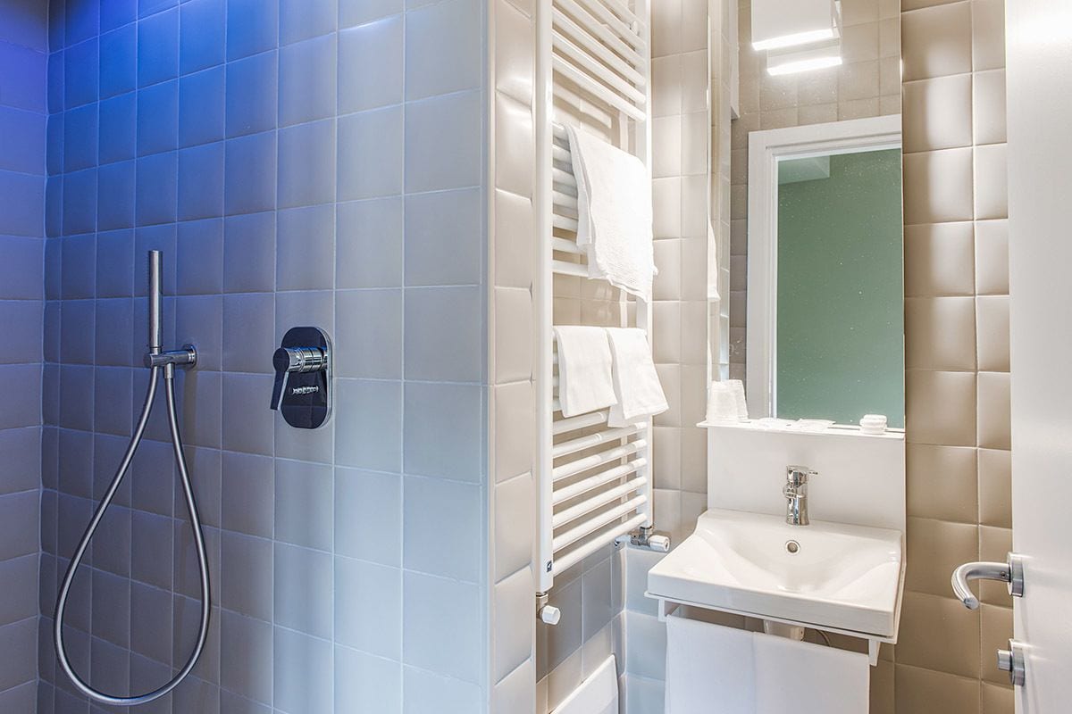 Een badkamer met een douche, wastafel en handdoekhouder.