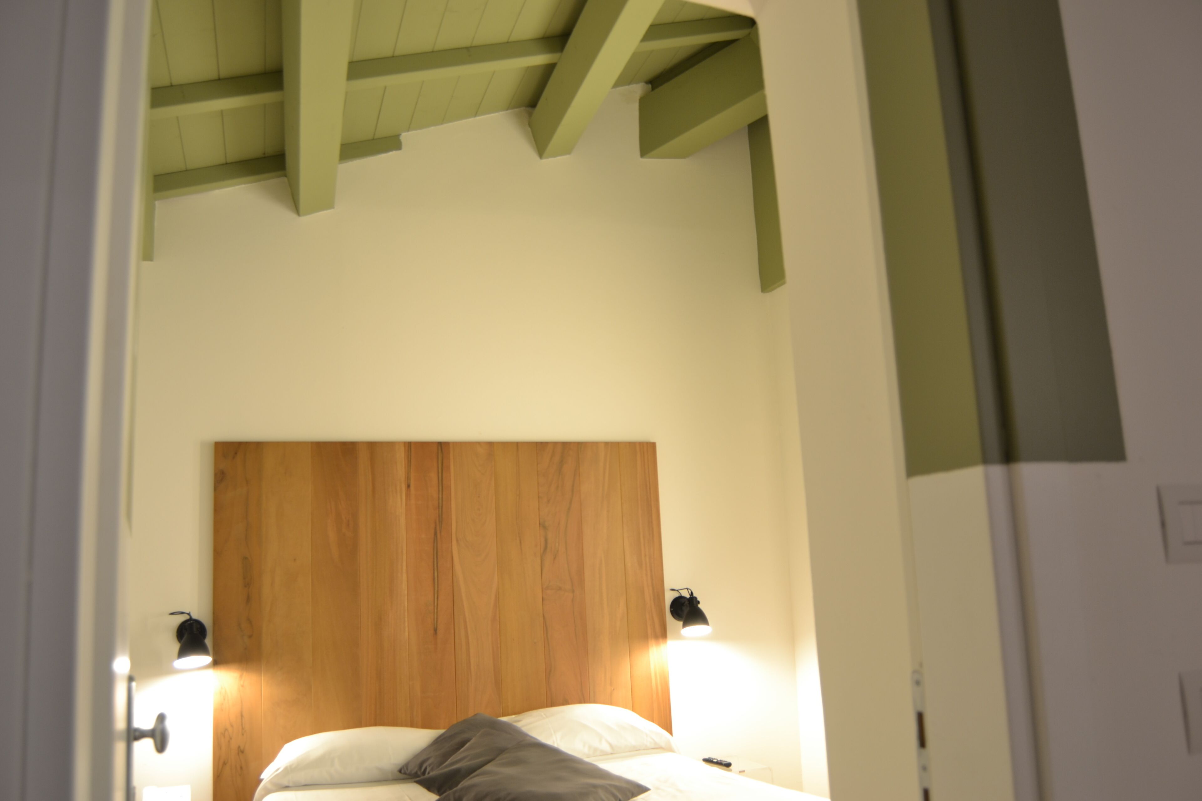 A bedroom with a wooden headboard, two bedside lamps, and a bed with pillows.