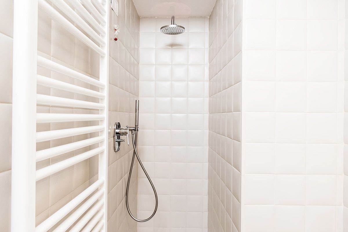 A modern shower with a handheld showerhead and a wall-mounted control valve.