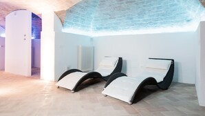A spa area with two reclining chairs, a radiator, and a stone ceiling. - Albergo Il Rientro (Cannara)